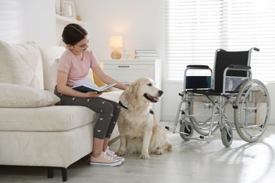 Photo of Girl with disability reading book and her service dog at home