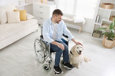Photo of Man in wheelchair with his service dog at home, above view