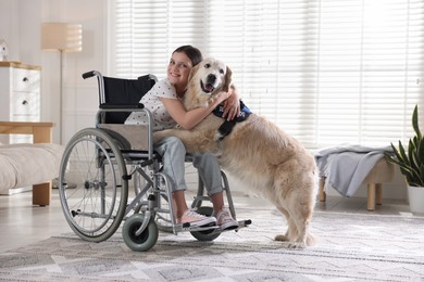 Photo of Girl in wheelchair hugging her service dog at home. Space for text