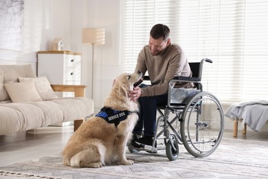 Photo of Man in wheelchair with his service dog at home