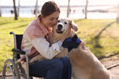 Photo of Woman in wheelchair hugging her service dog at park