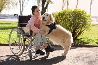 Photo of Girl in wheelchair hugging her service dog at park