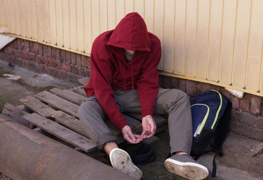 Photo of Homeless man counting coins on city street