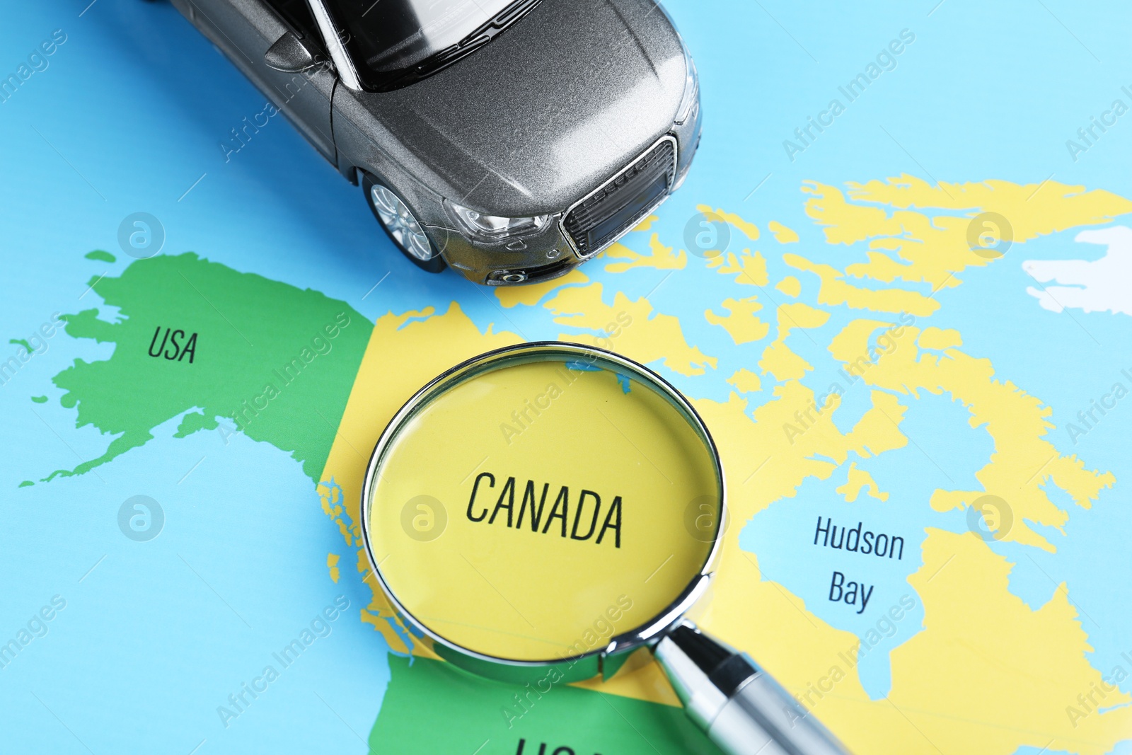 Road trip concept. Toy car and magnifying glass on world map, above view Photo of Road trip concept. Toy car and magnifying glass on world map, above view