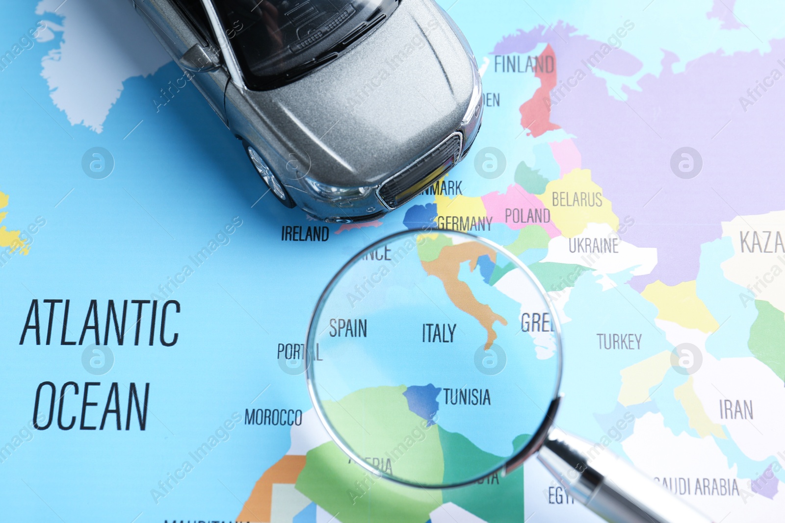 Road trip concept. Toy car and magnifying glass on world map, above view Photo of Road trip concept. Toy car and magnifying glass on world map, above view