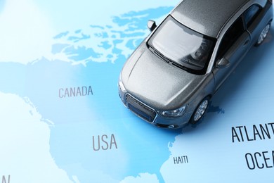 Photo of Road trip concept. Toy car on world map, above view