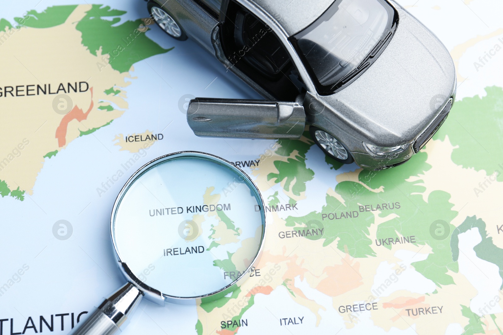 Road trip concept. Toy car and magnifying glass on world map, above view Photo of Road trip concept. Toy car and magnifying glass on world map, above view