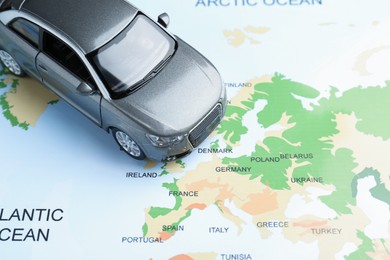 Photo of Road trip concept. Toy car on world map, above view