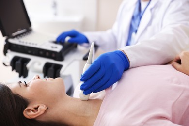 Photo of Sonographer conducting ultrasound examination of woman's thyroid gland in clinic, closeup