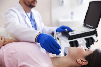 Photo of Sonographer conducting ultrasound examination of woman's thyroid gland in clinic, closeup