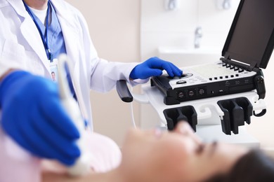 Photo of Sonographer conducting ultrasound examination of woman's thyroid gland in clinic, selective focus