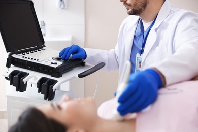 Photo of Sonographer conducting ultrasound examination of woman's thyroid gland in clinic, selective focus