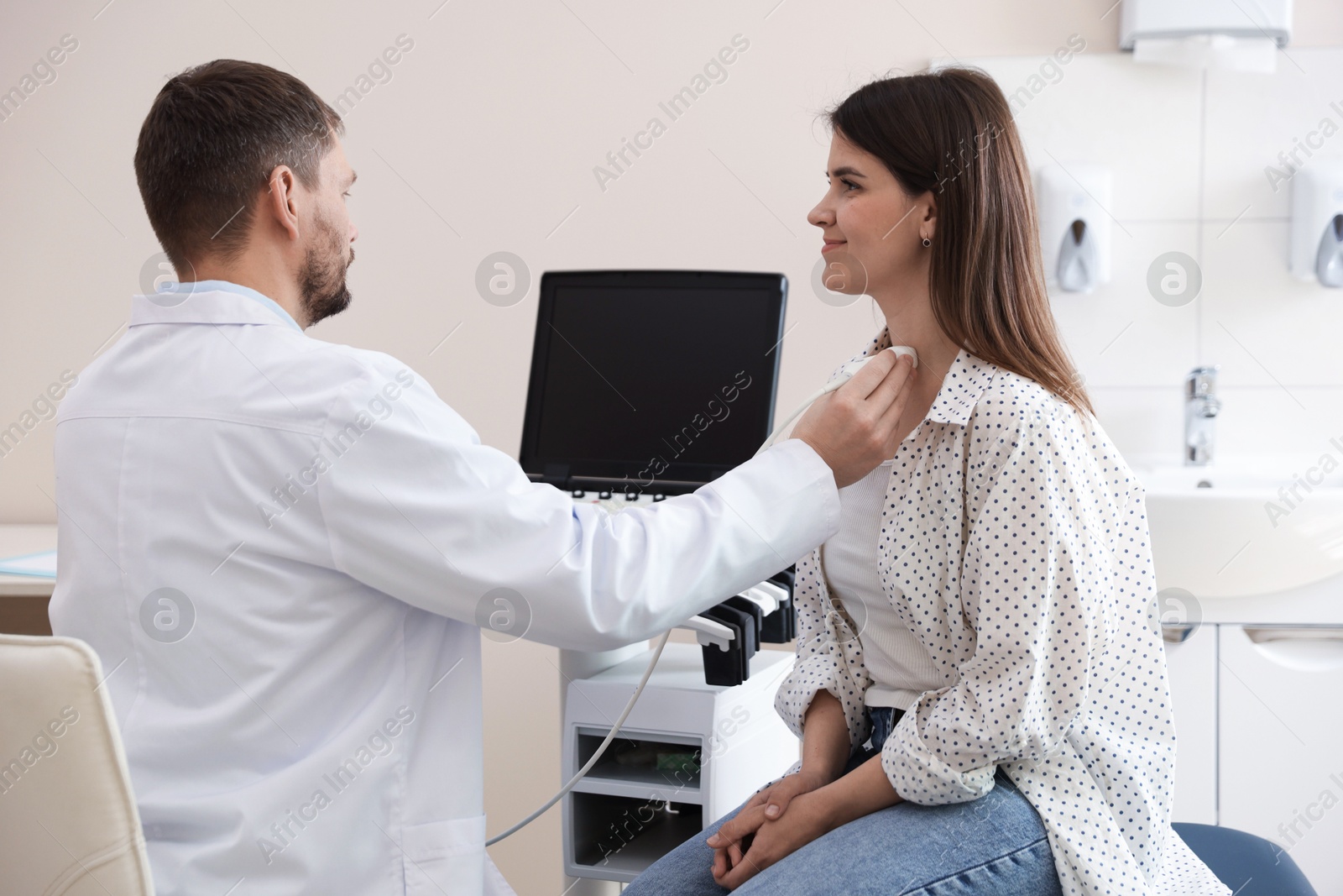 Sonographer conducting ultrasound examination of woman's thyroid gland in clinic Photo of Sonographer conducting ultrasound examination of woman's thyroid gland in clinic