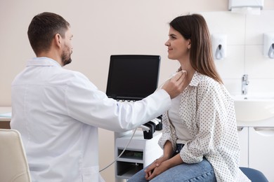 Photo of Sonographer conducting ultrasound examination of woman's thyroid gland in clinic