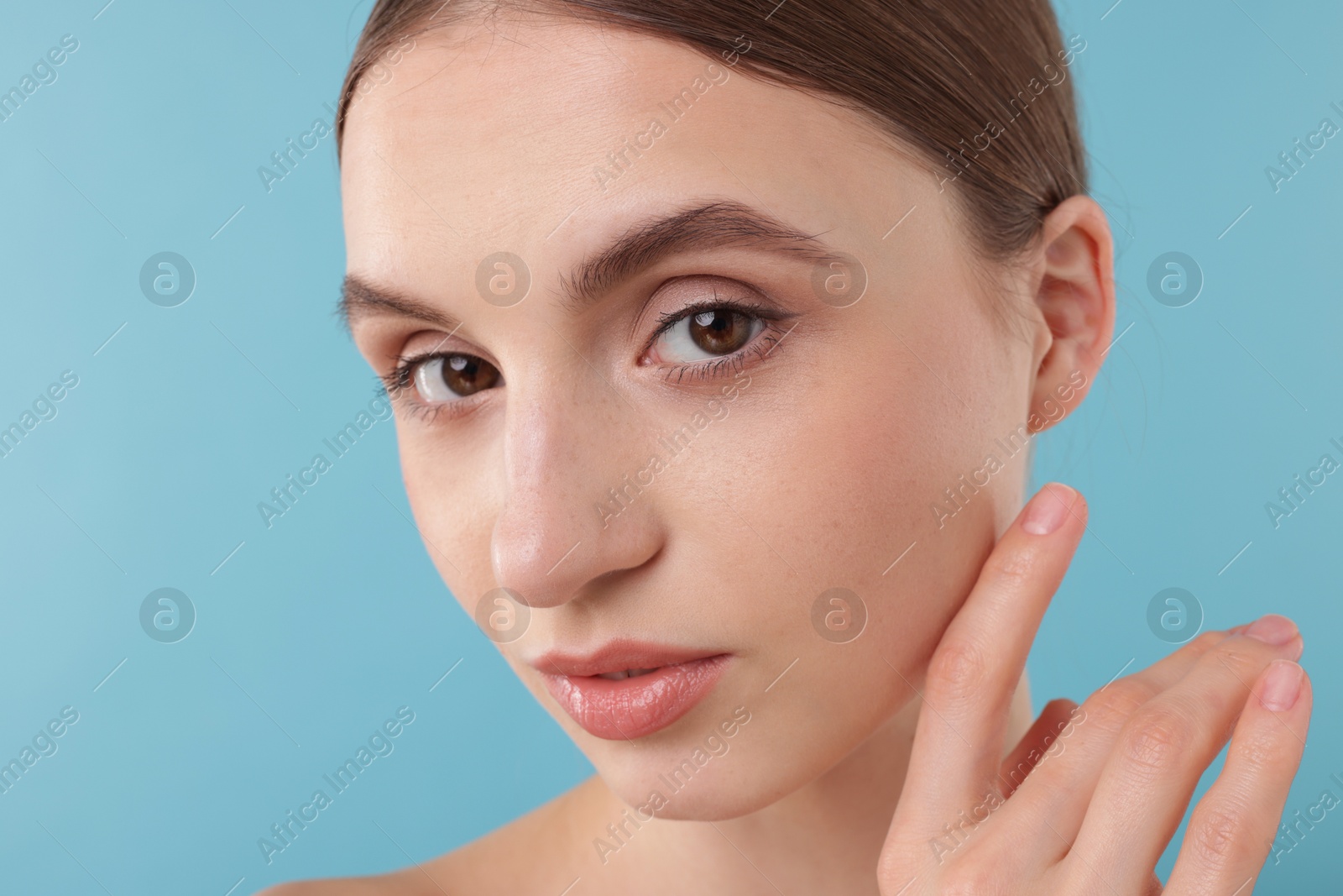 Portrait of charming young woman on light blue background Photo of Portrait of charming young woman on light blue background