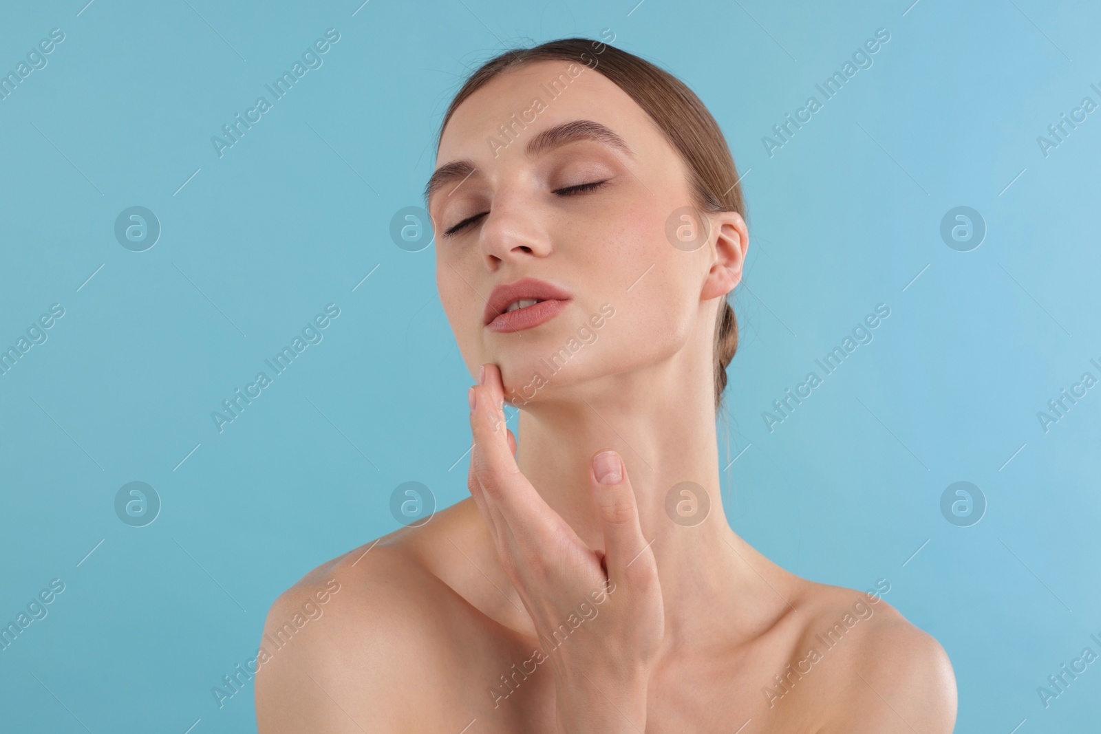 Portrait of charming young woman on light blue background Photo of Portrait of charming young woman on light blue background