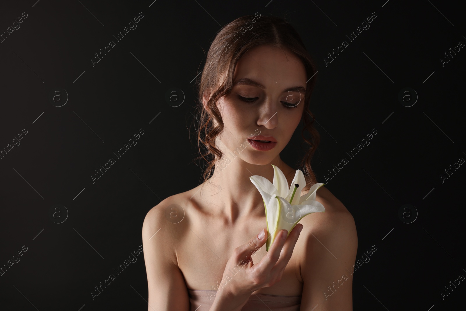 Portrait of gorgeous young woman with flower on black background Photo of Portrait of gorgeous young woman with flower on black background