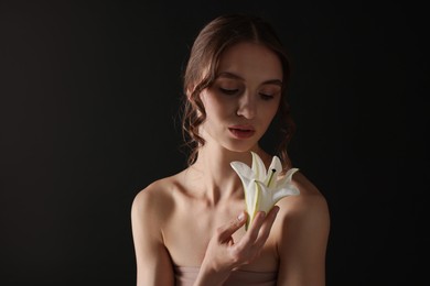 Photo of Portrait of gorgeous young woman with flower on black background