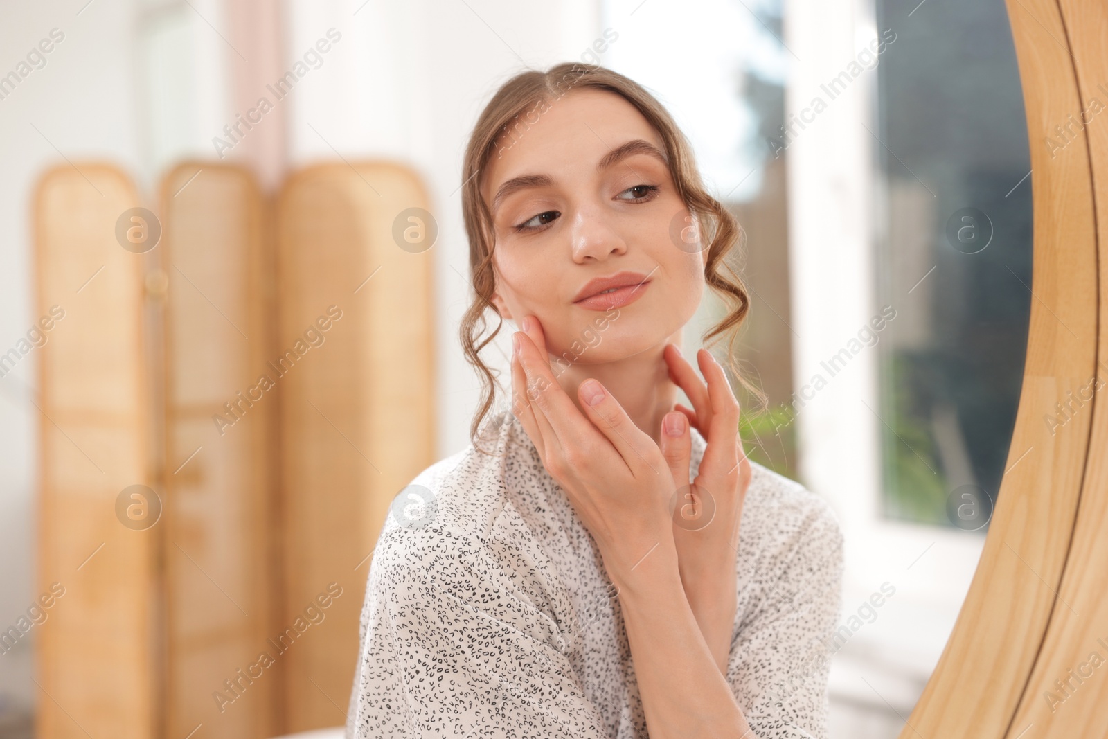 Beautiful woman looking at herself in mirror indoors Photo of Beautiful woman looking at herself in mirror indoors