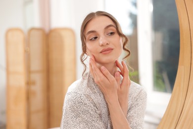 Photo of Beautiful woman looking at herself in mirror indoors