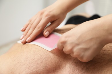 Photo of Young man undergoing wax epilation in salon, closeup