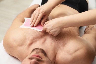 Photo of Young man undergoing wax epilation in salon, closeup