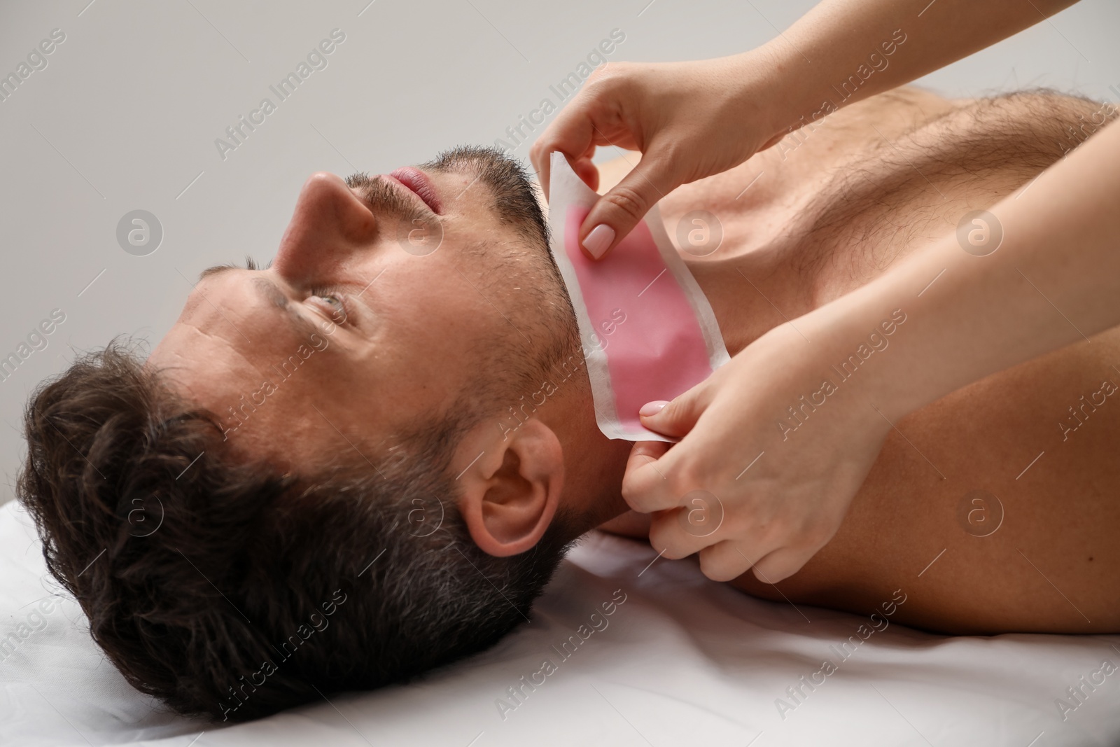 Photo of Young man undergoing wax epilation in salon