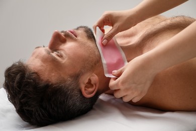 Photo of Young man undergoing wax epilation in salon