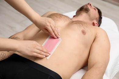 Photo of Young man undergoing wax epilation in salon