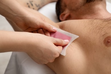 Photo of Young man undergoing wax epilation in salon, closeup