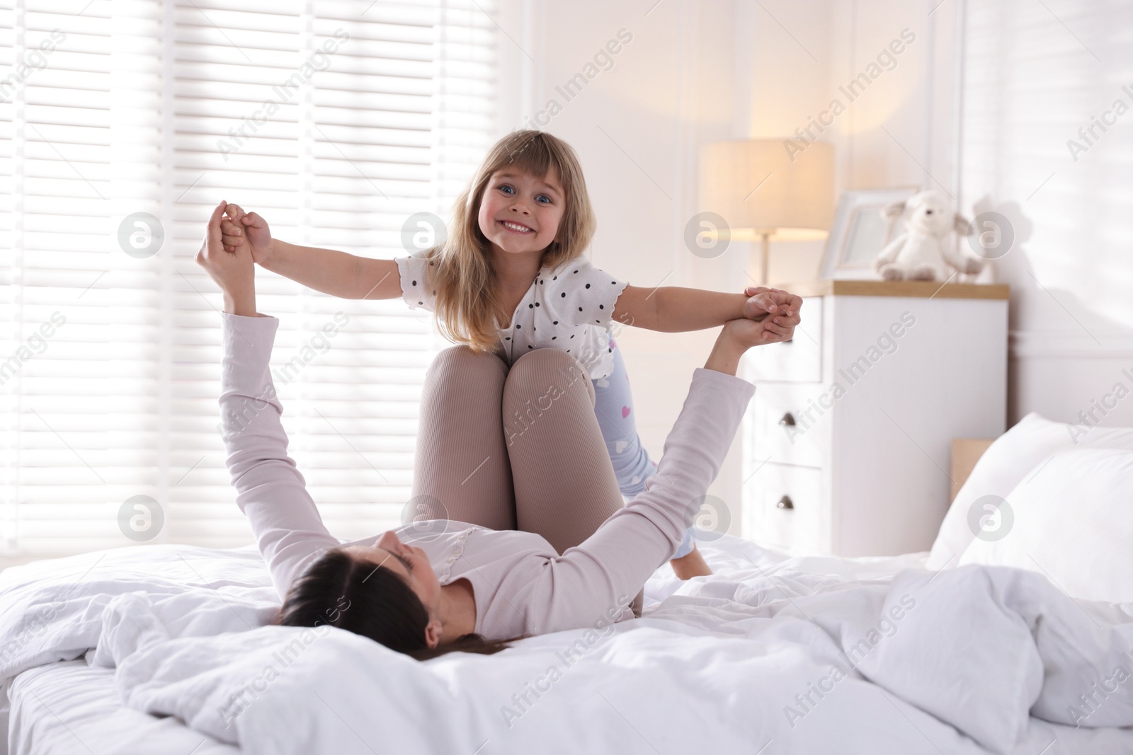 Mother and daughter having fun on bed at home Photo of Mother and daughter having fun on bed at home