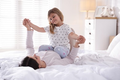Photo of Mother and daughter having fun on bed at home