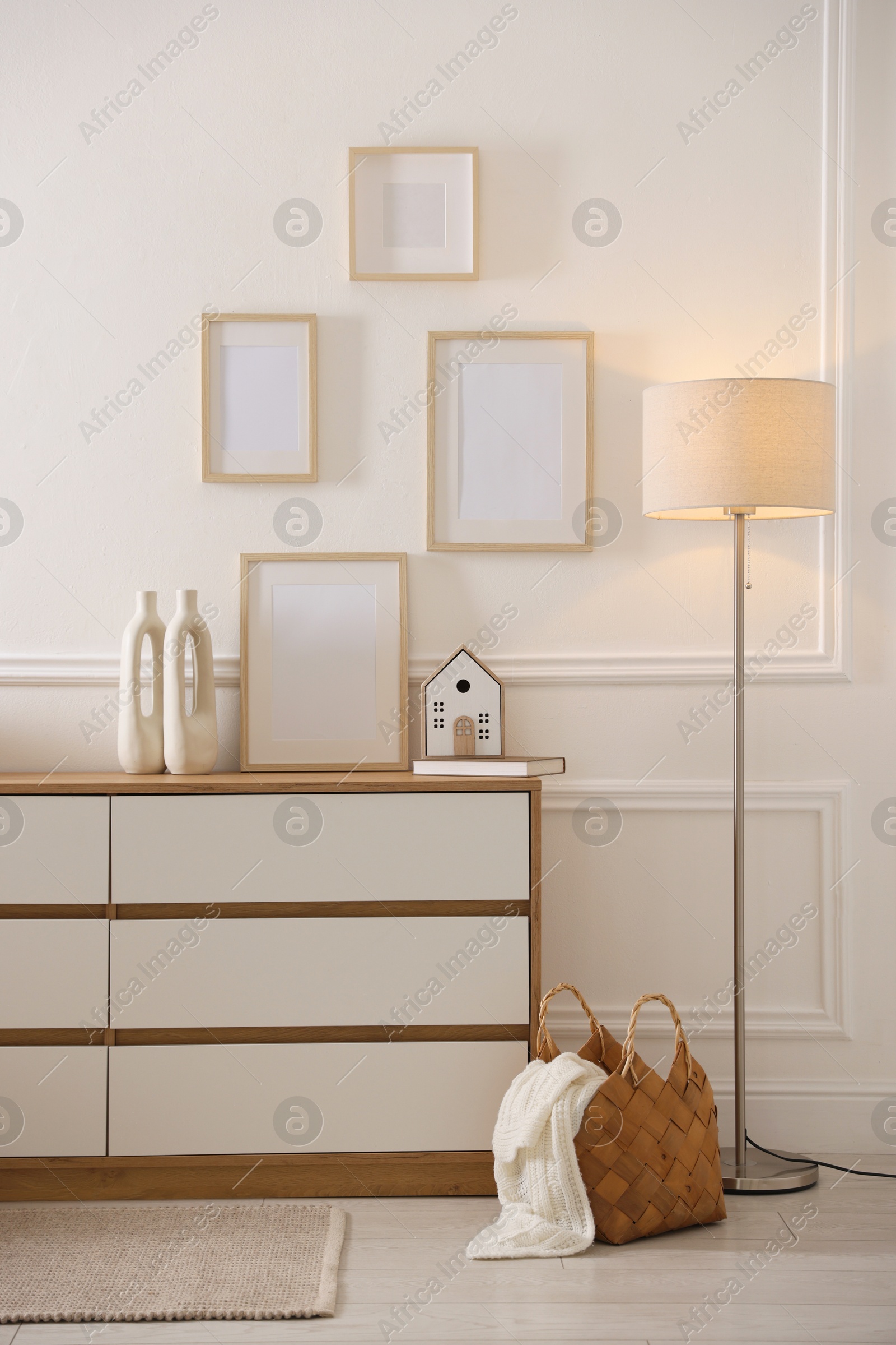 Blank frames on wall and chest of drawers indoors Photo of Blank frames on wall and chest of drawers indoors