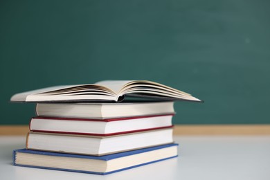 Photo of Stack of books on desk against chalkboard. Space for text