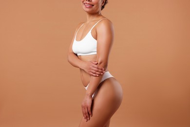 Photo of Woman in white underwear with smooth skin after epilation procedure on beige background, closeup