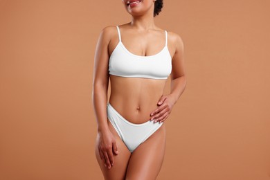 Photo of Woman in white underwear with smooth skin after epilation procedure on beige background, closeup
