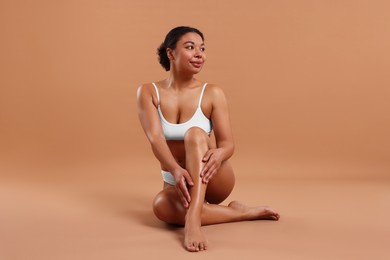 Photo of Woman in white underwear with smooth skin after epilation procedure on beige background