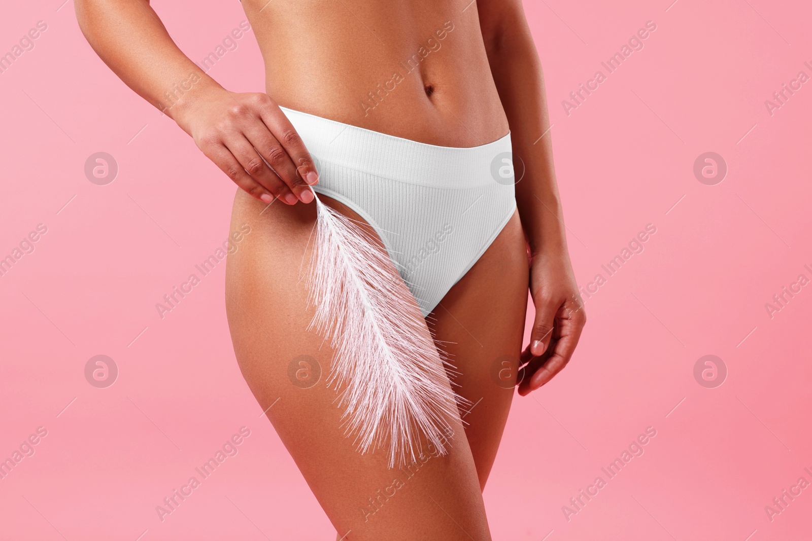 Woman in white underwear with feather showing smooth skin after epilation procedure on pink background, closeup Photo of Woman in white underwear with feather showing smooth skin after epilation procedure on pink background, closeup