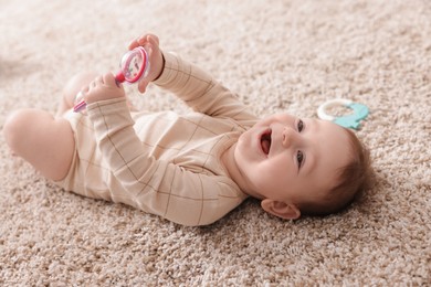 Photo of Cute little baby with rattle toy on floor at home