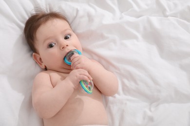 Photo of Cute little baby with rattle toy on bed at home, above view. Space for text