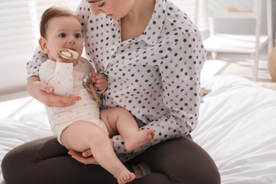 Photo of Mother and her cute little baby with rattle toy on bed at home, closeup