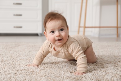 Photo of Cute little baby with rattle toy on floor at home