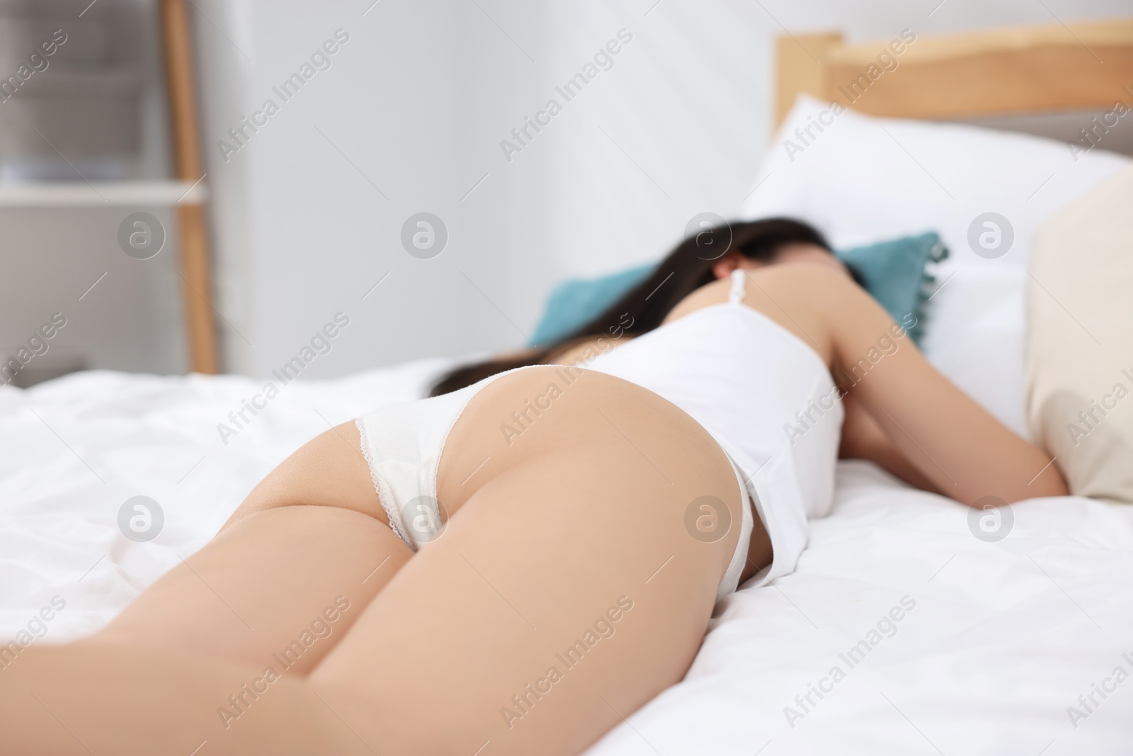 Woman in beautiful underwear lying on bed, closeup. Space for text Photo of Woman in beautiful underwear lying on bed, closeup. Space for text
