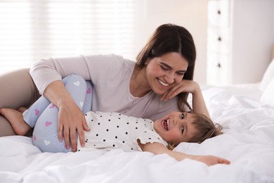 Photo of Mother and daughter having fun on bed at home