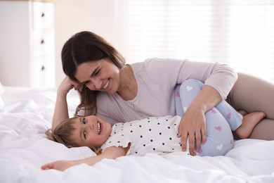 Photo of Mother and daughter having fun on bed at home