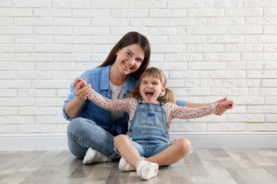 Photo of Beautiful mother and her little daughter near white brick wall