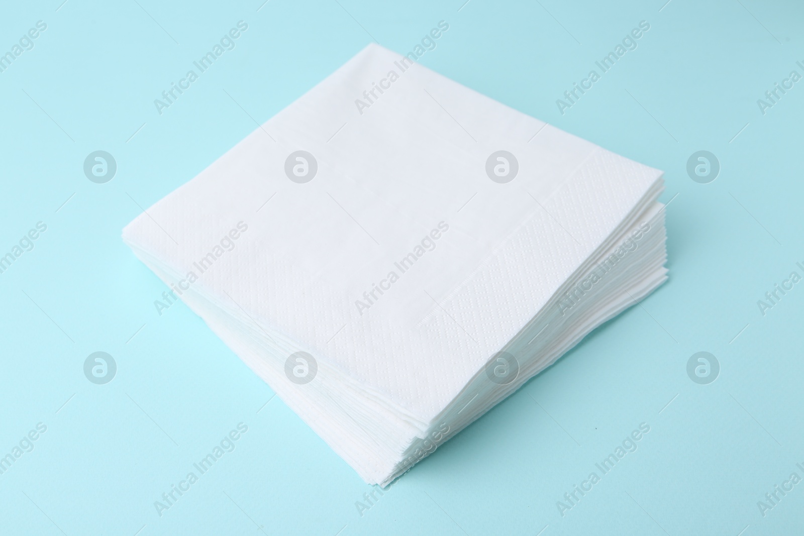 Stack of disposable paper handkerchiefs on light blue background, closeup Photo of Stack of disposable paper handkerchiefs on light blue background, closeup