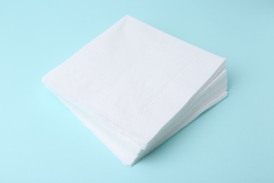 Photo of Stack of disposable paper handkerchiefs on light blue background, closeup
