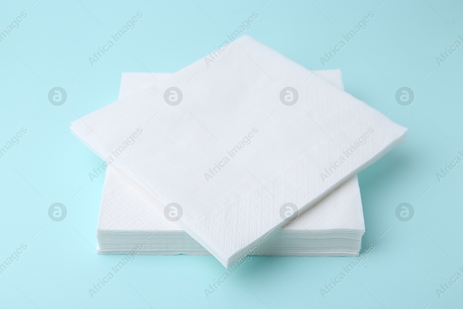 Stack of disposable paper handkerchiefs on light blue background, closeup Photo of Stack of disposable paper handkerchiefs on light blue background, closeup
