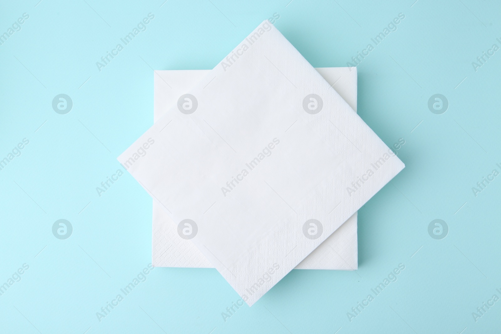 Stack of disposable paper handkerchiefs on light blue background, top view Photo of Stack of disposable paper handkerchiefs on light blue background, top view